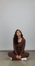 Woman sitting cross-legged on a plain background
