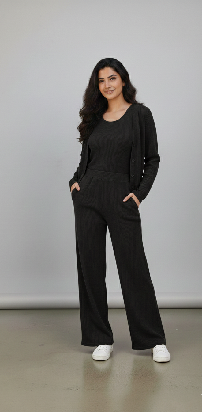 Woman wearing a black outfit standing against a plain background