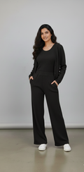 Woman wearing a black outfit standing against a plain background