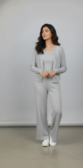 Woman wearing a gray outfit standing against a plain background