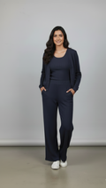 Woman wearing a navy blue outfit with a matching cardigan against a plain background