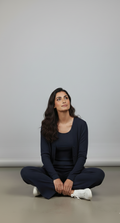 Woman sitting cross-legged on a plain background