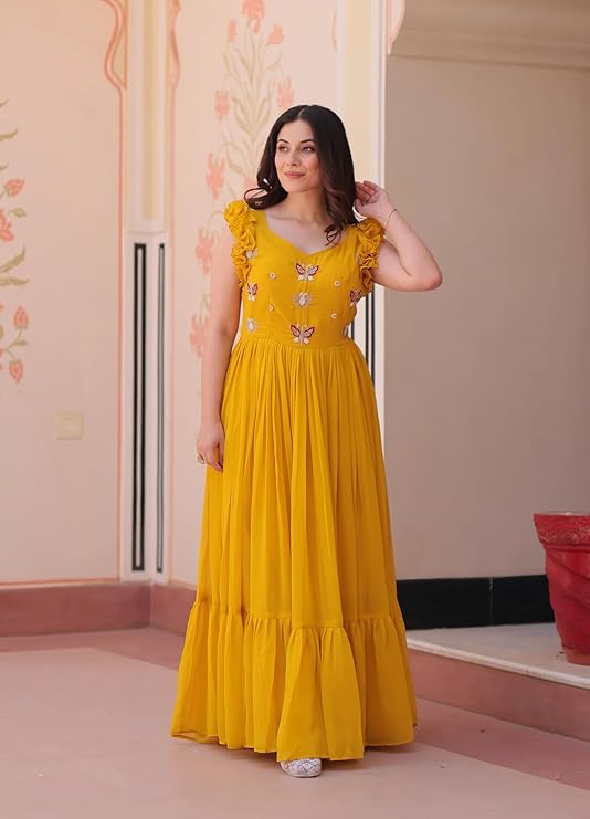 Woman wearing a yellow dress with floral patterns indoors.