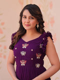 Woman wearing a purple dress with butterfly designs against a beige background