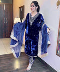 Woman wearing a blue traditional outfit with a matching dupatta indoors.