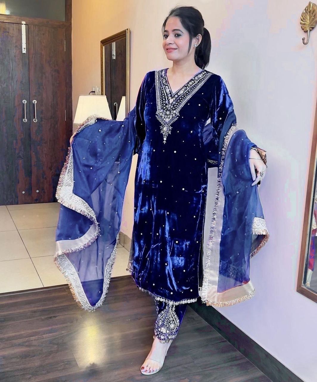 Woman wearing a blue traditional outfit with a matching dupatta indoors.