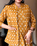 Woman wearing a mustard yellow patterned outfit with a blurred background