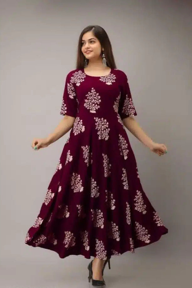 Woman wearing a maroon dress with white floral patterns on a gray background