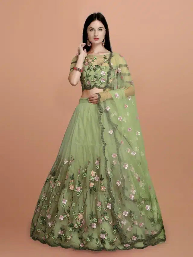 Woman wearing a green embroidered lehenga with a plain background