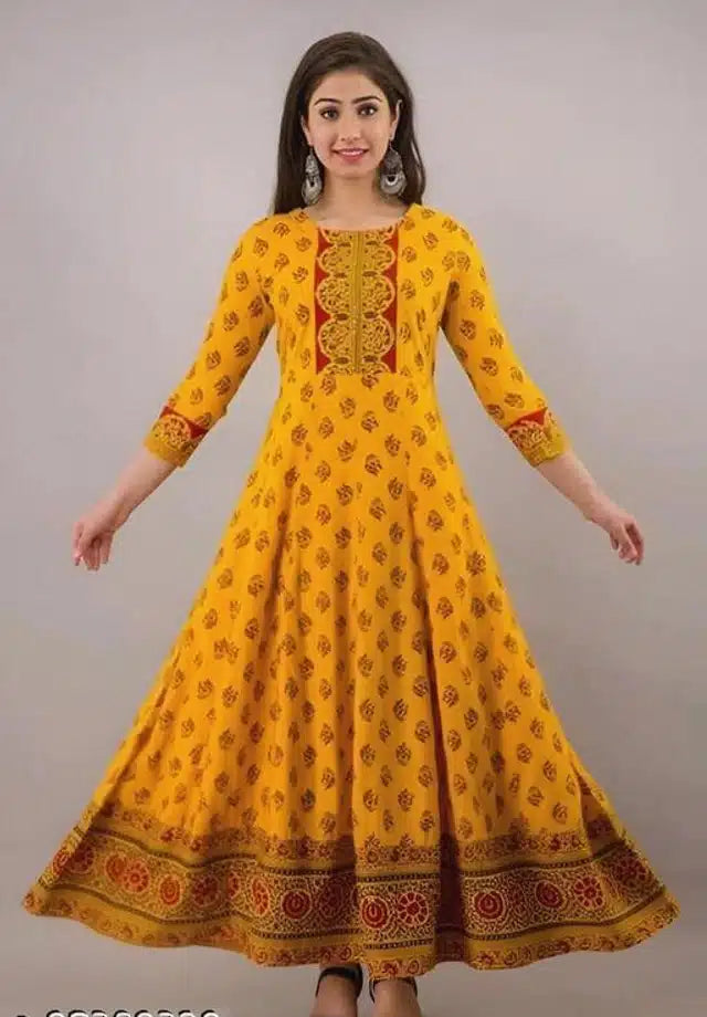 Woman wearing a yellow traditional dress with intricate patterns on a gray background