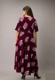 Woman wearing a maroon dress with white floral patterns on a gray background