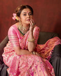 Woman in a pink saree with jewelry against a brown background