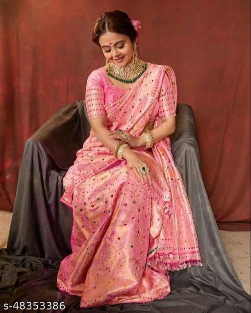 Woman in a pink saree with jewelry against a brown background