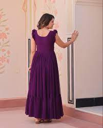 Woman in a purple dress standing in front of a mirror.