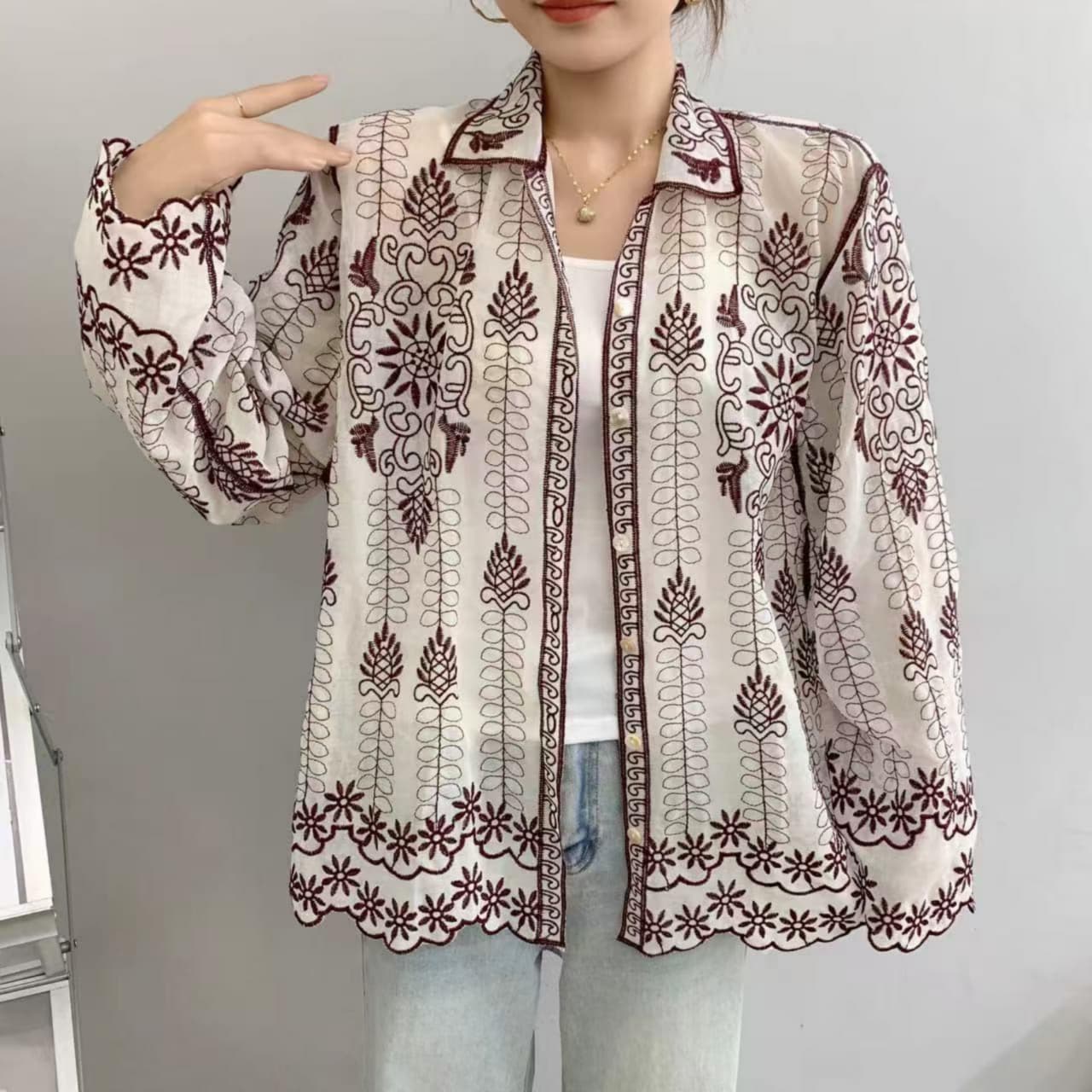 Person wearing a patterned blouse with a plain background